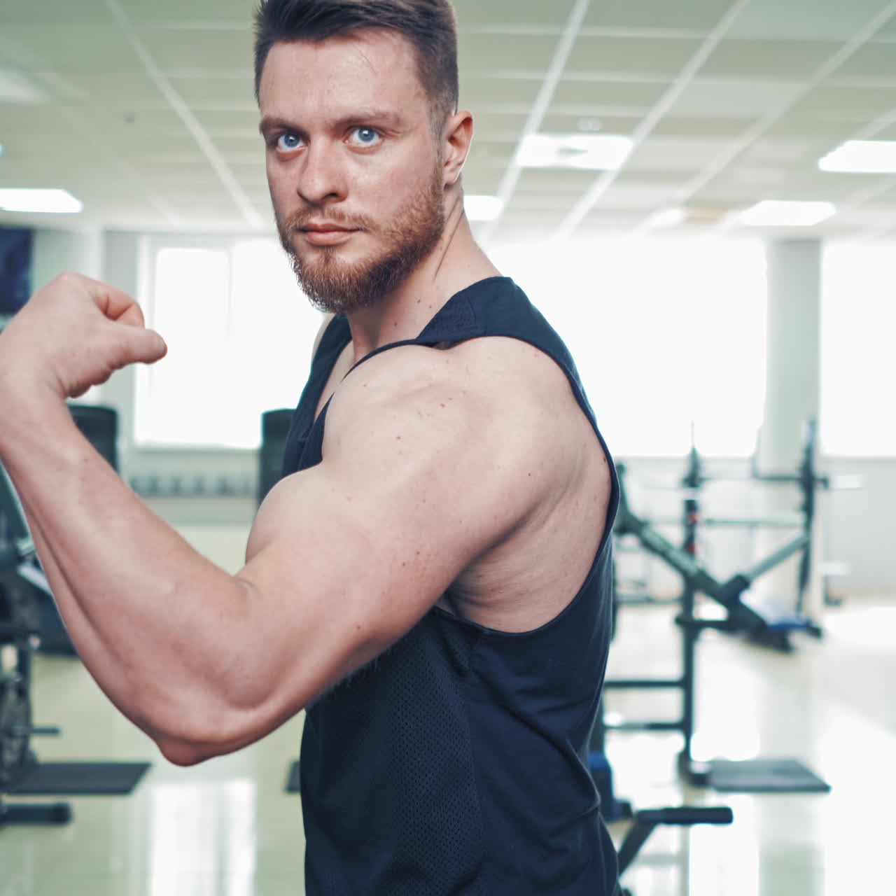 Close-up muscles on man's arm in sports club. Strong bodybuilder in sportswear showing his biceps in fitness center.