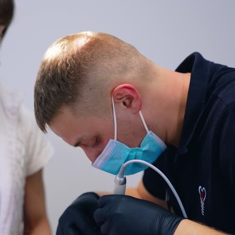 Dentist and a nurse in protective masks work in clinic. Professional male stomatologist treating teeth with dental tools. Work of dentist. Healthcare and medicine concept. Close-up