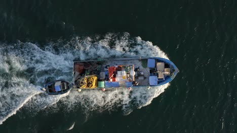 barco de pesca cargado con aparejos de pesca en su camino hacia el mar dejando un rastro blanco detrás de él