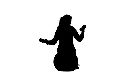 silhouette of woman lifting dumbbells on exercise ball