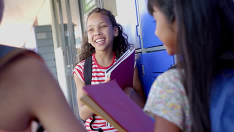 three biracial girls are chatting outside a classroom in school