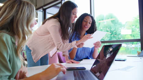 Equipo-De-Negocios-Femenino-Multicultural-Sentado-En-El-Escritorio-Con-Una-Computadora-Portátil-En-La-Oficina-Colaborando-En-El-Proyecto