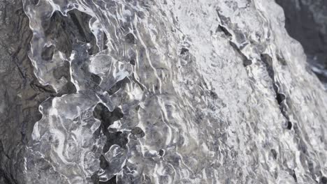 water flows over a rock and melting clear ice