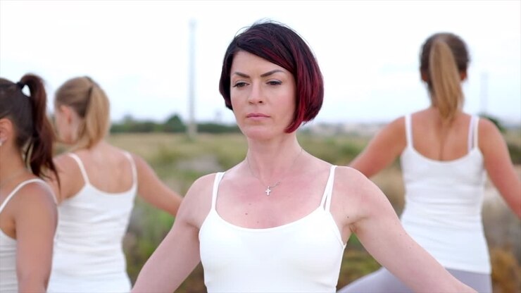 Sei donne caucasiche serene di 40 anni in piedi in cerchio eseguono la posizione dell'albero