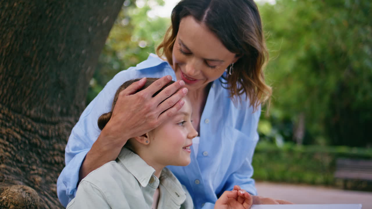 Little child reading fairytale for mom in park closeup. Mother kid enjoying book
