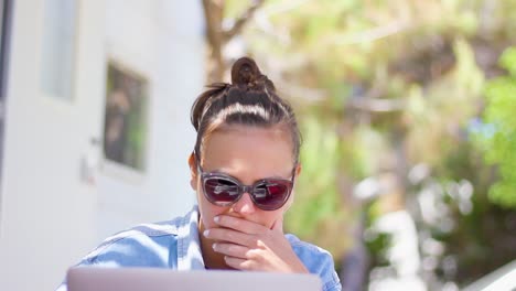 mujer que trabaja de forma remota al aire libre con una computadora portátil como nómada digital, toma estática