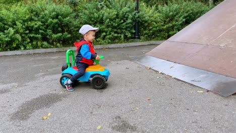 joyful kid on the toy car tries to get on the slide. baby boy on the sports ground outdoors.
