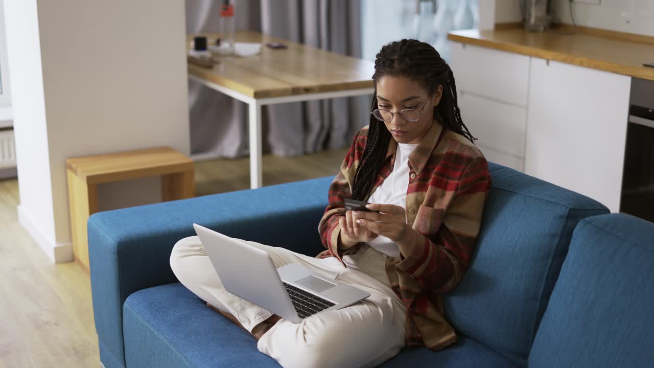 Young african american holding credit card using a digital mobile device and buying online