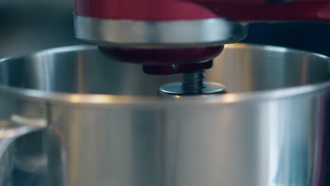 mixer gradually spins in big metal bowl to prepare cream