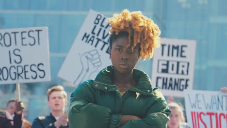 portrait of female protestor amongst marchers with placards on black lives matter demonstration