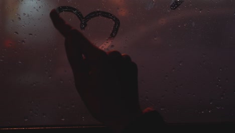 the glass of the window is swamped. young girl with forefinger draws a symbol of love and heart. st. valentine's day