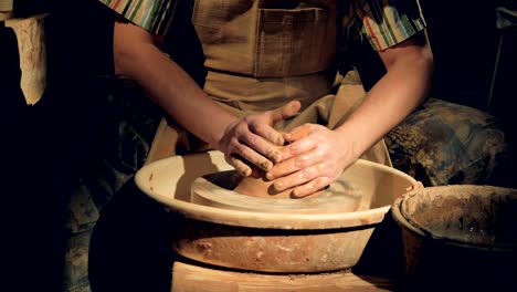 a potter wets a large lump of clay on a wheel.