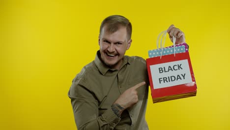 Mann-Zeigt-Die-Aufschrift-„Black-Friday“-Auf-Einkaufstüten,-Lächelt,-Zufrieden-Mit-Einkäufen-Zu-Niedrigen-Preisen