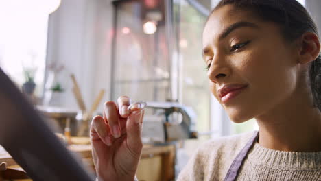 joyera comparando un anillo con un diseño dibujado en una tableta digital en un estudio