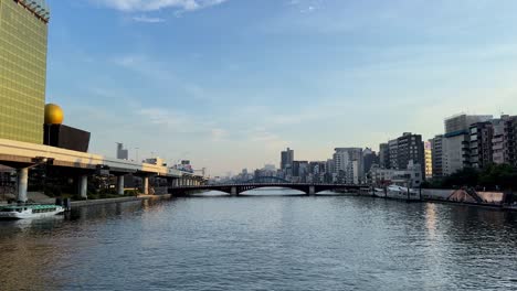 Cityscape-view-of-a-serene-river-with-bridges-and-buildings-during-a-clear-afternoon