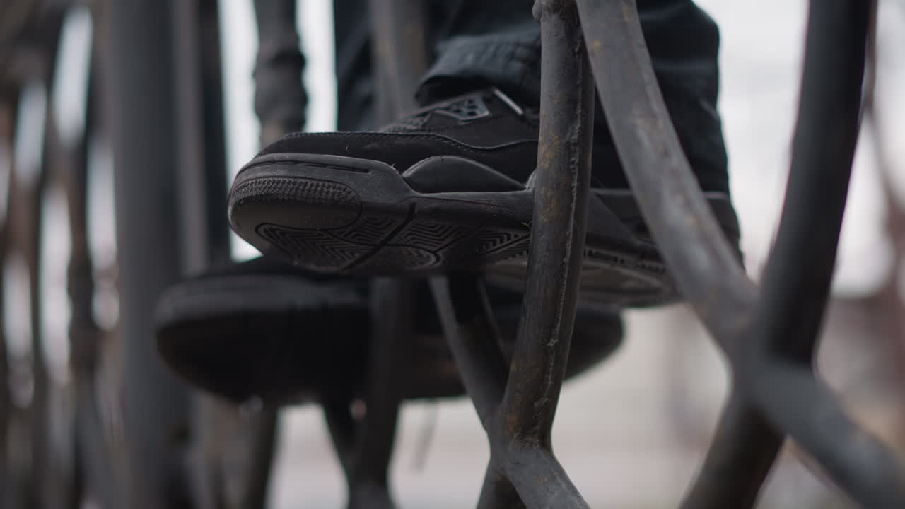 Urban rooftop tense. Woman on railing with sneakers. Reflective wet street beneath tense cinematic urban scene. Woman perches above street on railing with sneakers gripping rusty iron surface