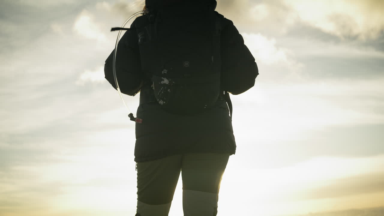 Tilting shot showing a hiker standing at the edge taking in the views at sunrise