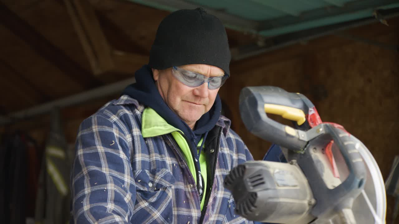 A construction worker uses a table saw to cut a piece of wood. He admires it after.