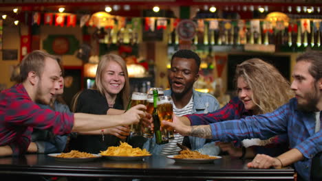 un grupo diverso de amigos celebran con un brindis y gritan vasos levantados con varias bebidas en la celebración. jóvenes hermosos se divierten en el elegante bar o restaurante.