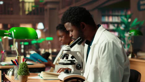 estudiante masculino investigando virus durante el análisis al microscopio y la lectura académica