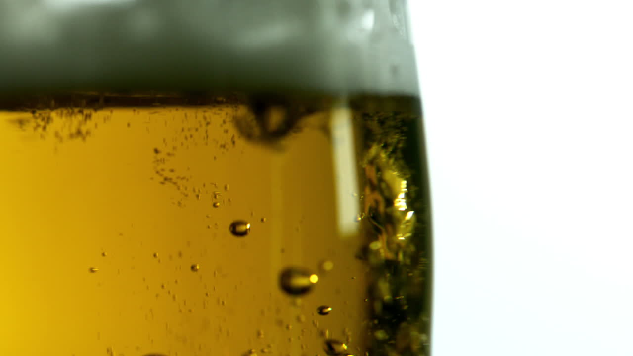 Glass of beer bubbling on white background