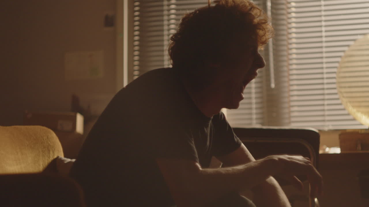 좌절 된 남자 가 집 에서 감정적 인 붕괴 를 겪으면서 소리 지르고 울고 있다