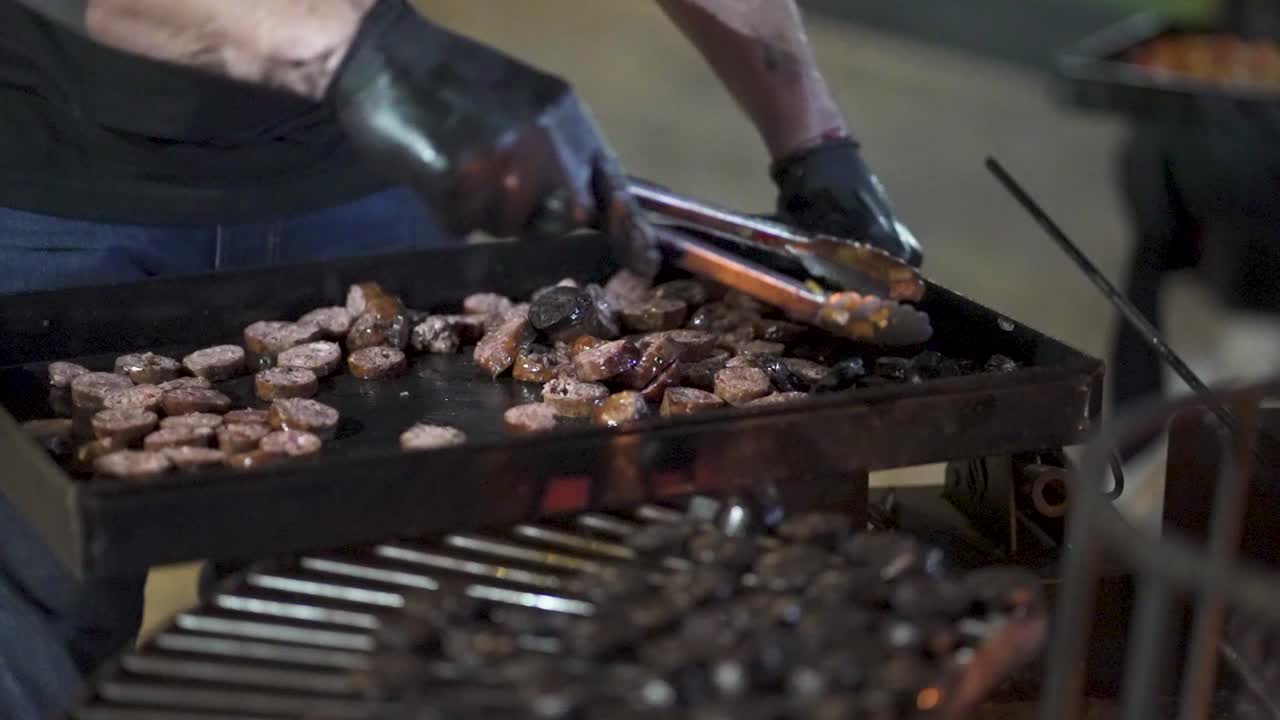 Grill master putting grilled meat being prepared on barbecue at food festival