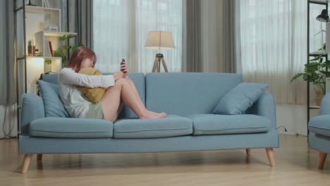 woman sitting on couch with phone