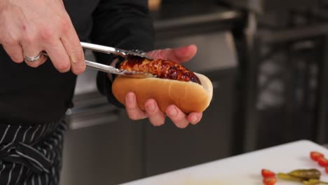 chef preparando un perrito caliente en una cocina