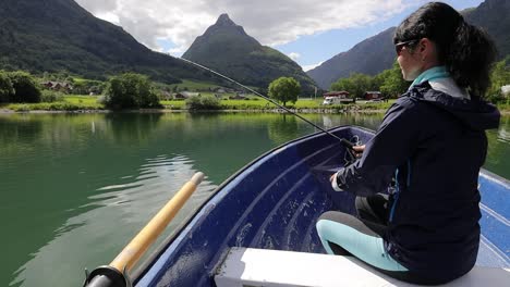 woman on the boat catches a fish on spinning in norway.