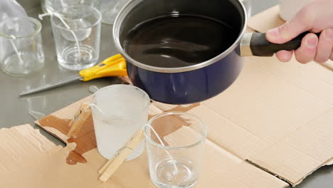 pouring hot wax into glass jars for homemade candles