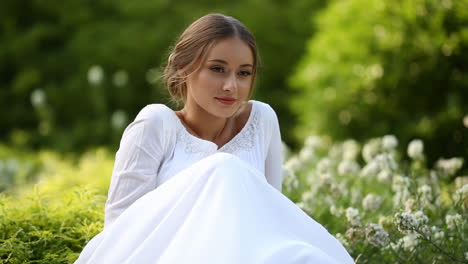 young woman in white dress sitting peacefully in a garden