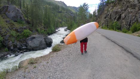 man carrying kayak up riverside road slow motion