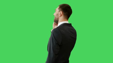 medium shot of a handsome man talking on the phone while camera revolves around him. shot on a green screen background.
