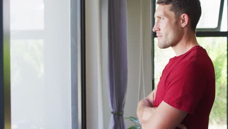 Thoughtful-caucasian-man-with-crossed-arms-looking-at-the-window