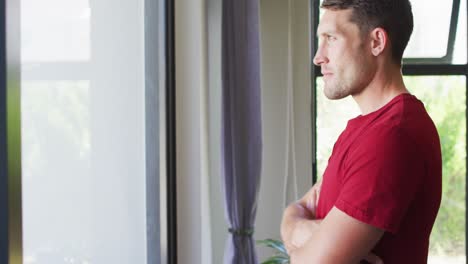 thoughtful caucasian man with crossed arms looking at the window