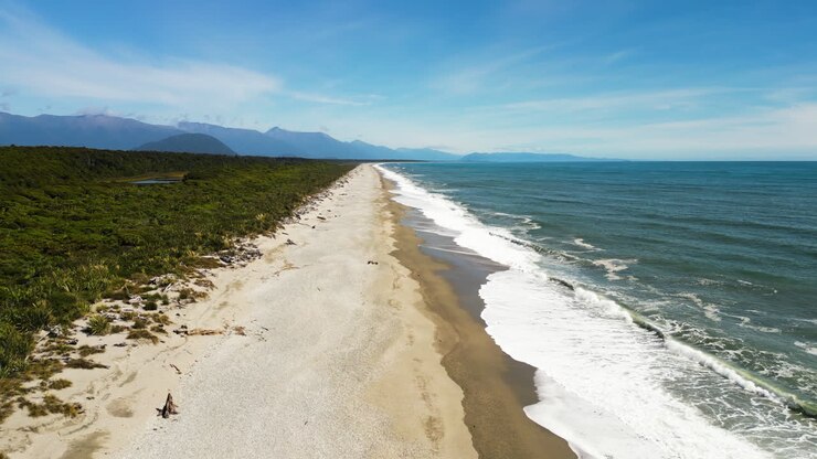 Drohnenaufnahme: Beruhigende Meereslandschaft mit Dünenstrand an der abgelegenen Westküste Neuseelands.