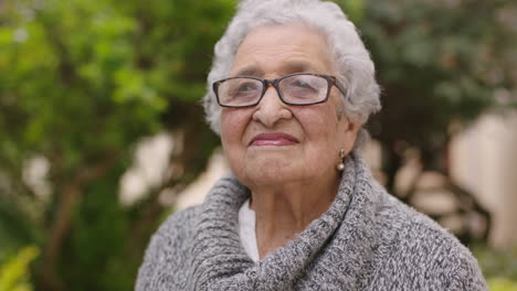 retrato en primer plano de una mujer de raza mixta de edad avanzada sonriendo disfrutando del jardín al aire libre sintiéndose tranquila y pacífica usando un suéter