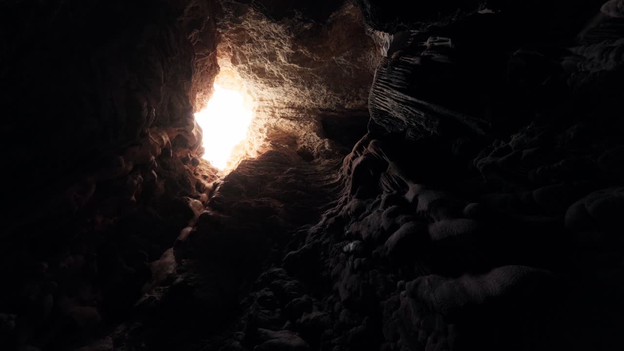 Rotating shot inside Ibiza cave looking up at sunlight entering through rocky opening