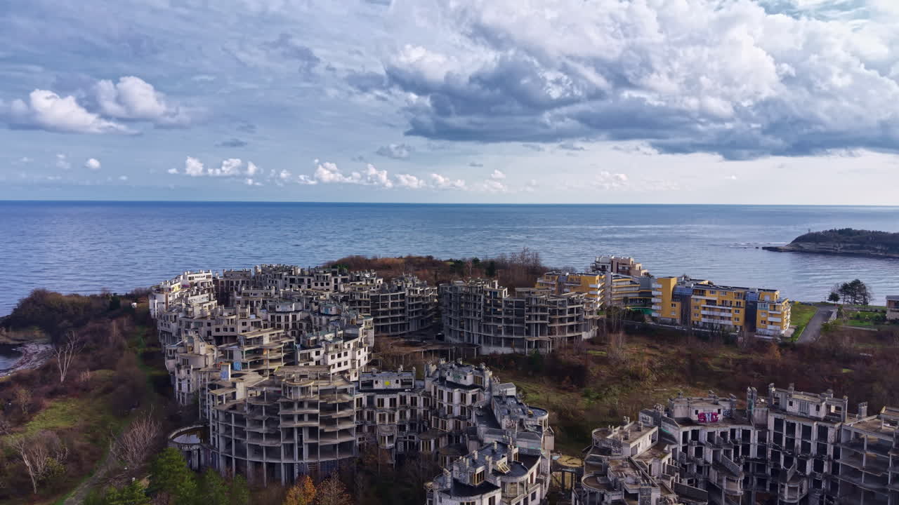 Haunting ruins of a coastal development abandoned by time, where nature reclaims its space beneath dramatic cloud-filled skies