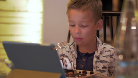 niño comiendo y viendo el touch pad en la cafetería