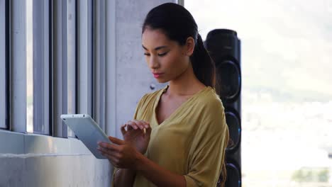 Executive-standing-near-window-and-using-digital-tablet