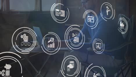 animación de iconos digitales sobre hombre caucásico usando portátil en casa.