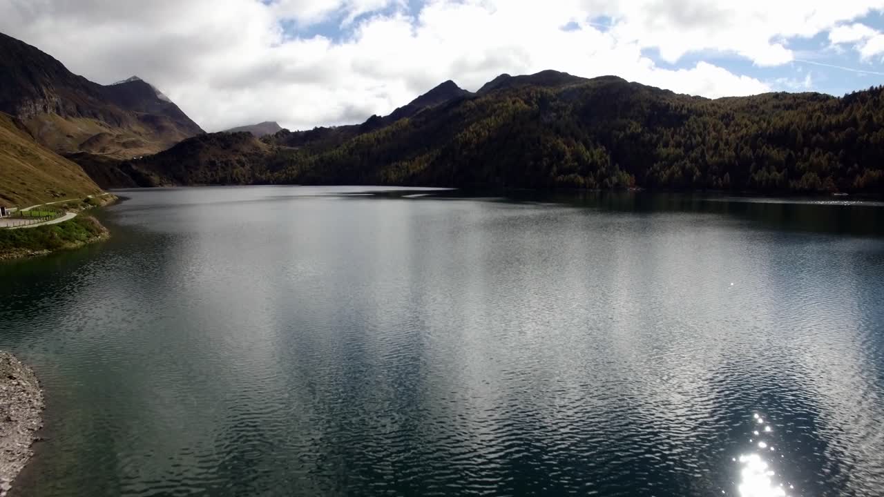 vista aérea del lago de montaña en suiza durante el otoño con bosque de pinos de colores, día de otoño nublado con montañas nevadas, lago ritom