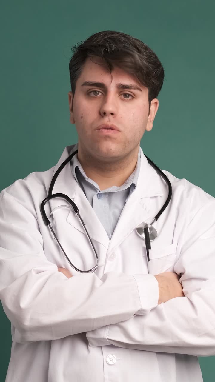 Dokter muda pria yang marah dan stres berteriak terisolasi dengan latar belakang hijau.