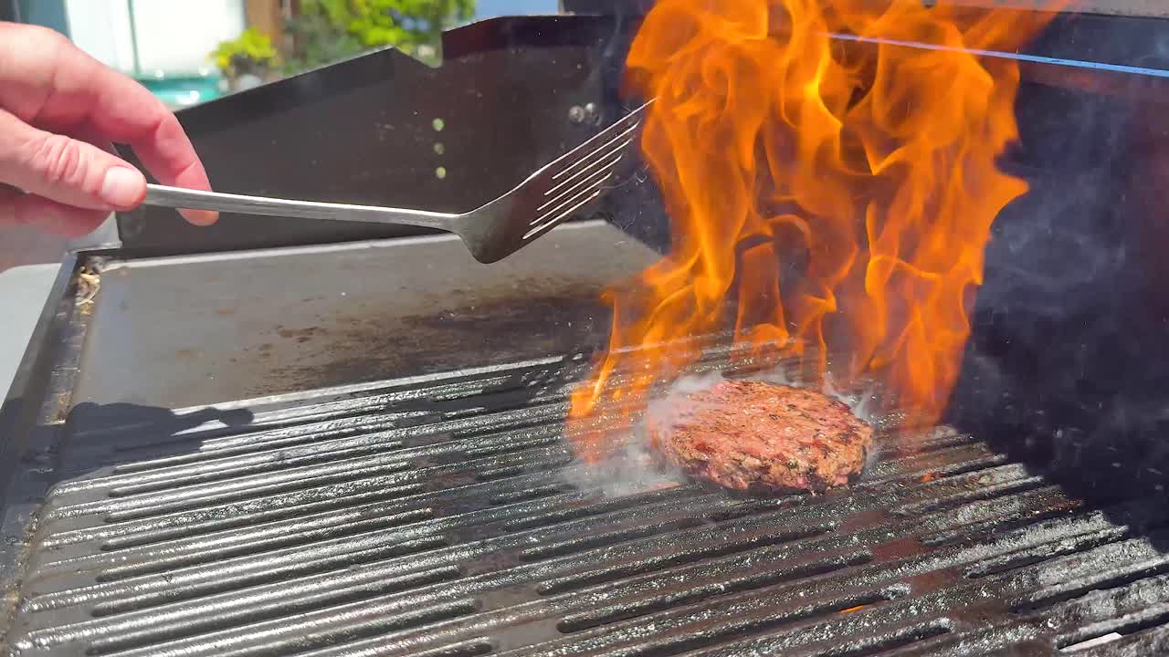 햄버거 패티를 는 동안 불꽃과 연기가