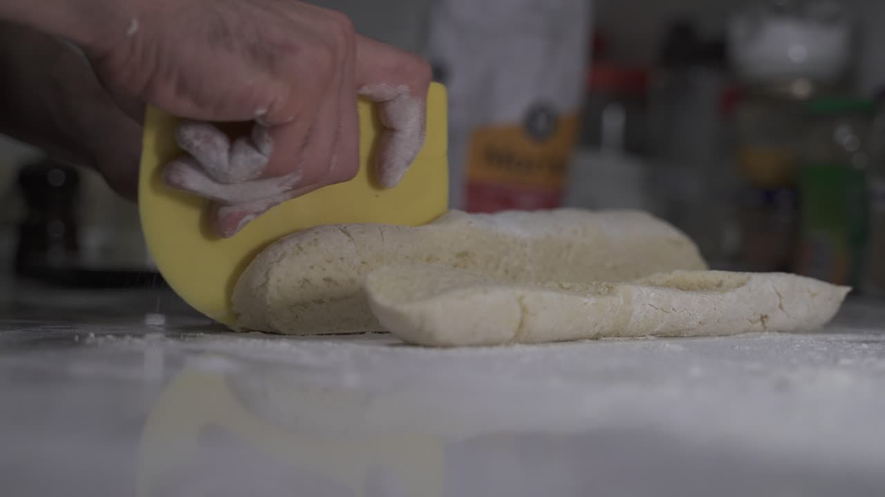 Close up of chef cutting fresh dough in pieces in kitchen bakery