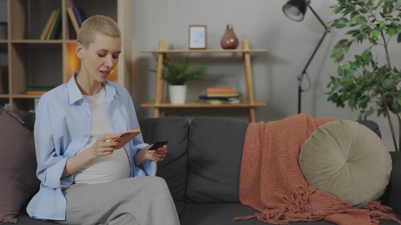 Pregnant Woman Using Smartphone and Credit Card at Home