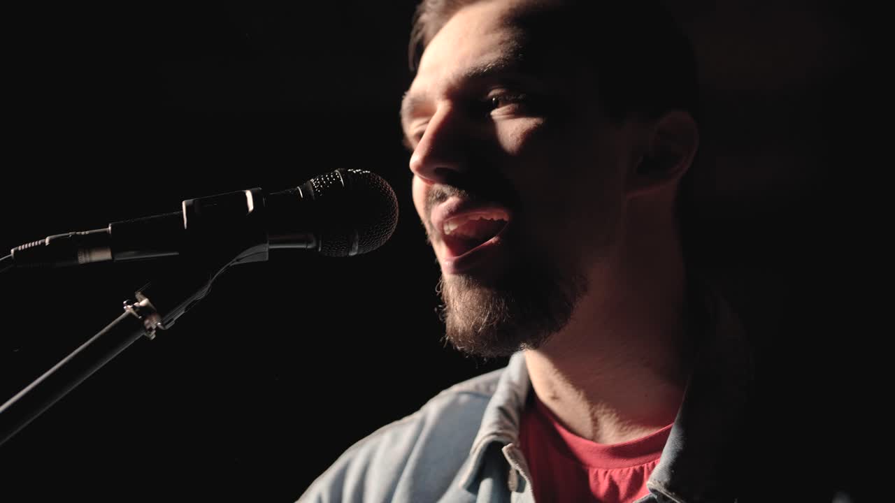 un músico está tocando la guitarra en un gran escenario con miembros de la audiencia sosteniendo linternas en el fondo. el auditorio está lleno de hermosas luces parpadeantes.