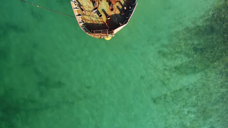 Top-down-drone-shot-of-a-shipwreck-on-the-Socotra-coast,-showing-the-rusted-remains-of-the-vessel-surrounded-by-turquoise-waters-and-rocky-shoreline